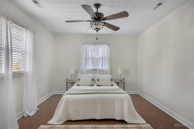 bedroom featuring multiple windows, dark wood-style floors, and visible vents