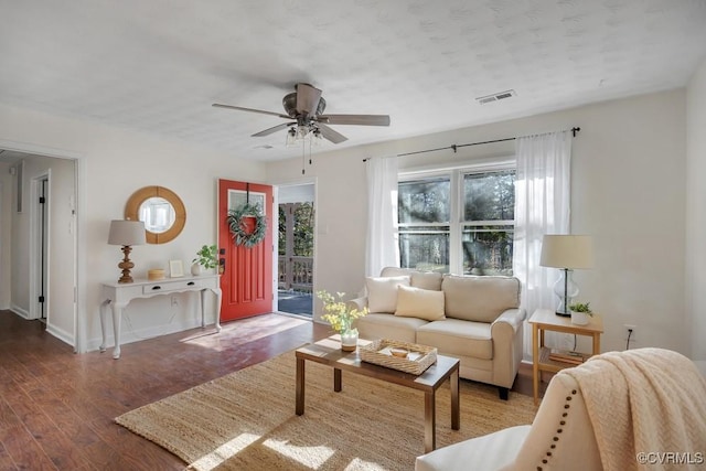 living area with visible vents, baseboards, wood finished floors, and a ceiling fan