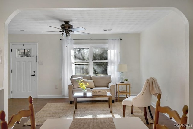 sitting room featuring visible vents, baseboards, ceiling fan, wood finished floors, and arched walkways