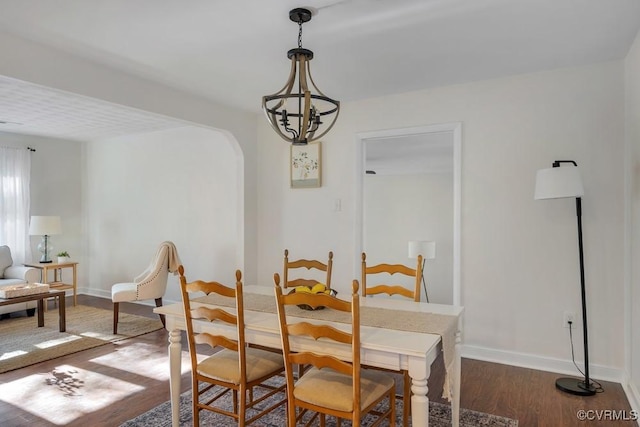 dining space with baseboards, arched walkways, and wood finished floors