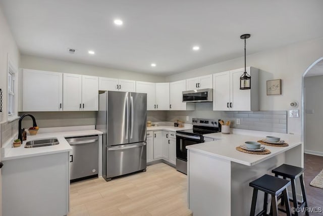 kitchen featuring a peninsula, light countertops, appliances with stainless steel finishes, and a sink