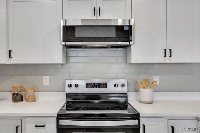 kitchen featuring light stone counters, decorative backsplash, appliances with stainless steel finishes, and white cabinetry