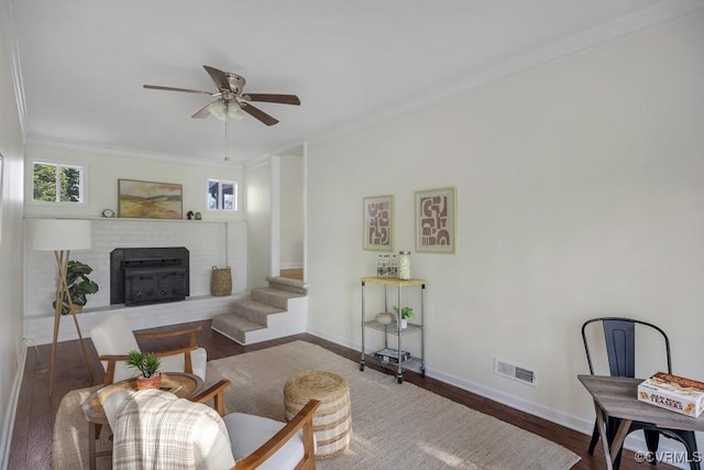 living area featuring ornamental molding, wood finished floors, baseboards, and ceiling fan