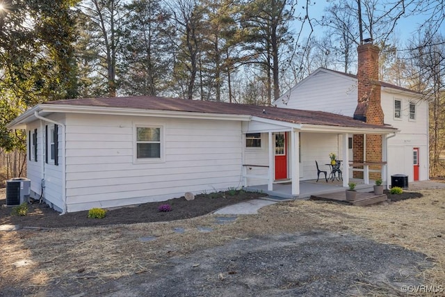 view of front of home with a porch, central AC unit, and a chimney