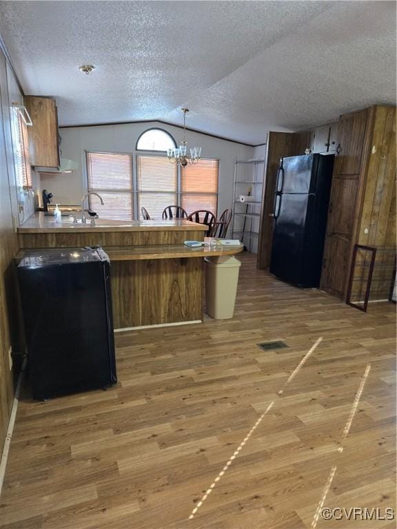 kitchen with freestanding refrigerator, light wood-style floors, a peninsula, dishwashing machine, and vaulted ceiling