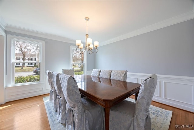 dining room featuring a chandelier, light wood-style flooring, and crown molding