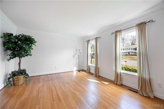 empty room featuring visible vents, crown molding, light wood-type flooring, and baseboards