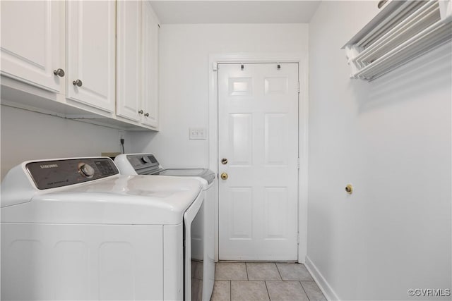 clothes washing area with light tile patterned floors, cabinet space, baseboards, and washing machine and clothes dryer