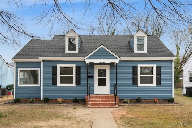 new england style home featuring a front yard and a shingled roof