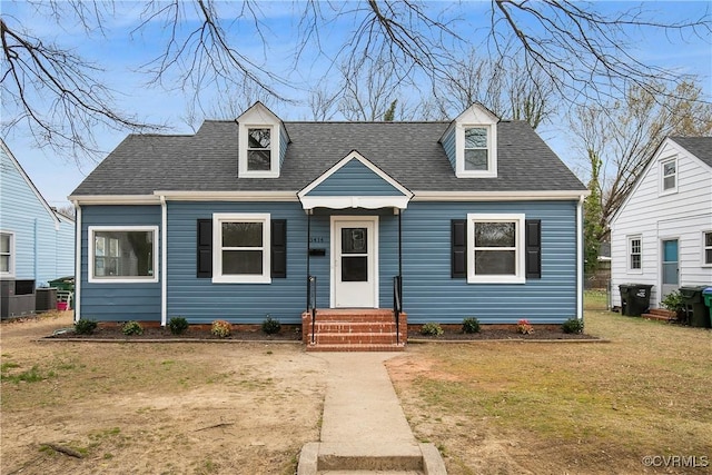 cape cod home with cooling unit, roof with shingles, and a front lawn