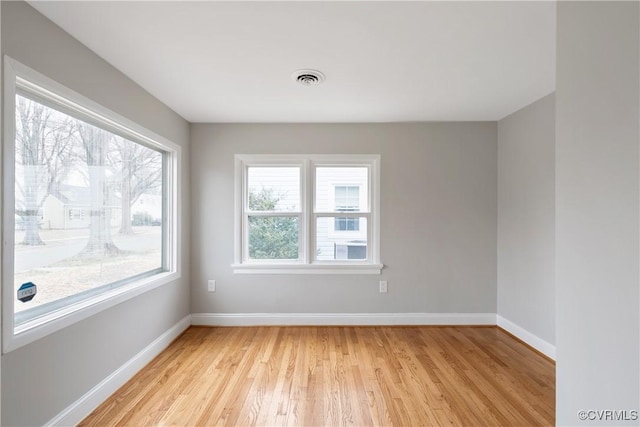 empty room featuring visible vents, baseboards, and light wood finished floors