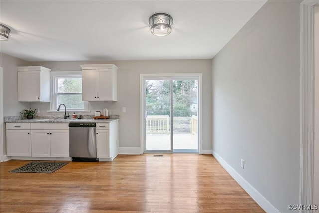 kitchen featuring baseboards, white cabinetry, light wood-style flooring, a sink, and stainless steel dishwasher