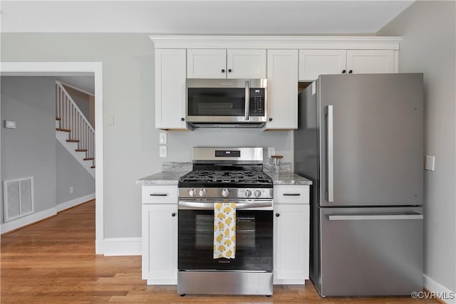 kitchen with light stone counters, visible vents, appliances with stainless steel finishes, and white cabinetry