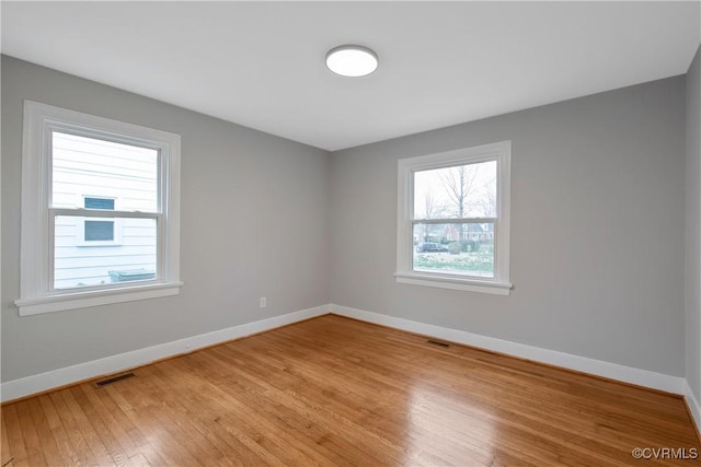 unfurnished room with visible vents, light wood-style flooring, and baseboards