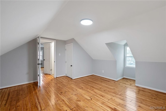 additional living space featuring lofted ceiling, light wood-style flooring, and baseboards