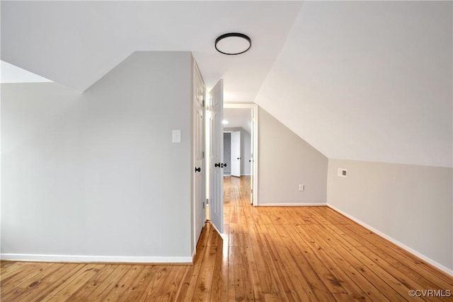 bonus room featuring light wood finished floors, baseboards, and vaulted ceiling