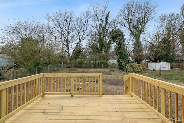 wooden deck featuring an outdoor structure, a fenced backyard, and a shed