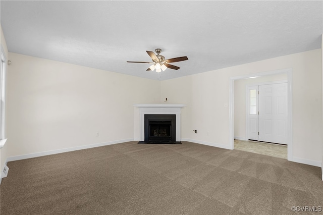 unfurnished living room with a ceiling fan, a fireplace with flush hearth, carpet, and baseboards