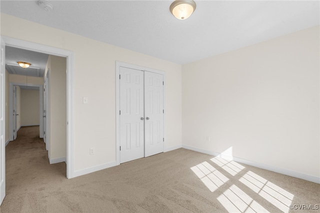 unfurnished bedroom with baseboards, attic access, and carpet