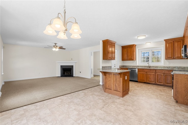 kitchen with brown cabinets, a fireplace with flush hearth, ceiling fan with notable chandelier, appliances with stainless steel finishes, and light colored carpet