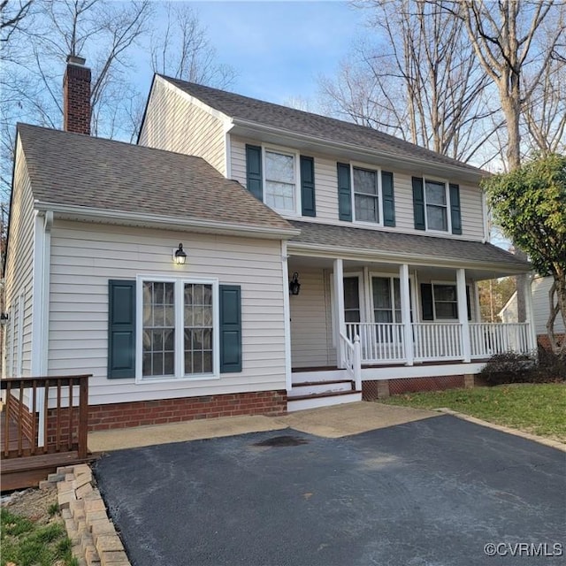 view of front of home featuring a porch, a chimney, and a shingled roof