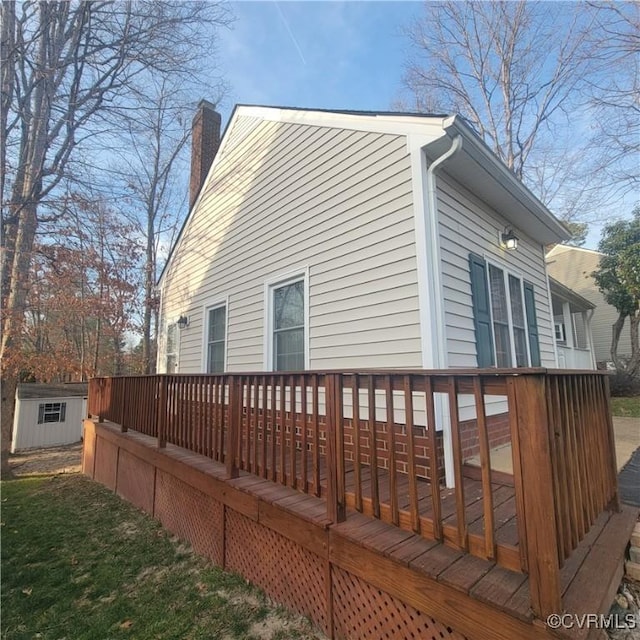 view of home's exterior featuring a deck, an outbuilding, a storage shed, and a chimney