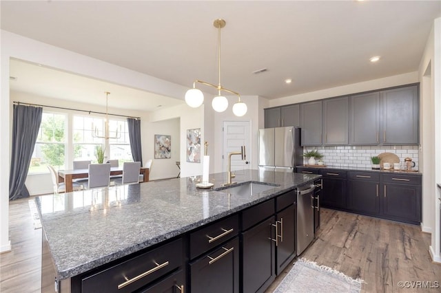 8160 Lyman Ct, Mechanicsville, VA 23116 - kitchen featuring appliances with stainless steel finishes, a kitchen island, dark stone counters, tasteful backsplash, and light wood-style floors