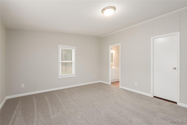 unfurnished bedroom with connected bathroom, baseboards, crown molding, and carpet