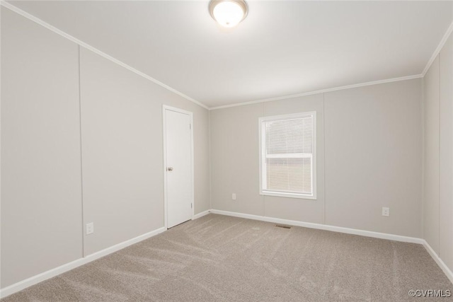 spare room featuring carpet flooring, baseboards, visible vents, and ornamental molding