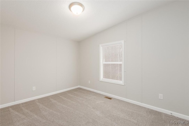 unfurnished room featuring vaulted ceiling, visible vents, and carpet floors