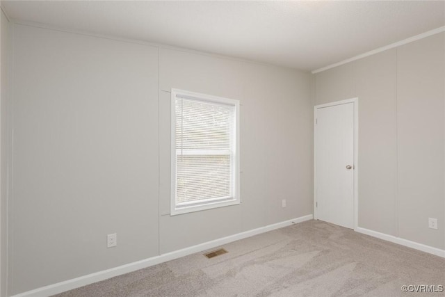 carpeted empty room with visible vents, baseboards, and crown molding