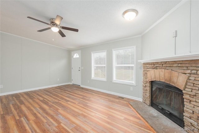 unfurnished living room featuring baseboards, light wood-style flooring, ceiling fan, ornamental molding, and a glass covered fireplace