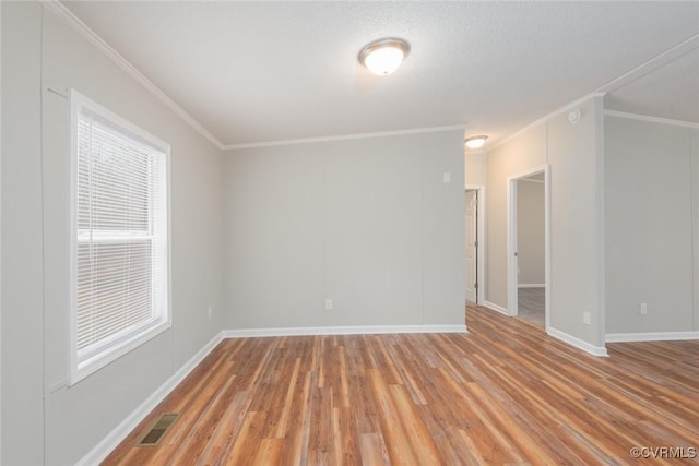 unfurnished room with visible vents, baseboards, crown molding, and light wood finished floors