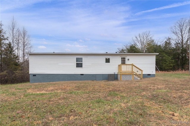 rear view of property with crawl space and a lawn