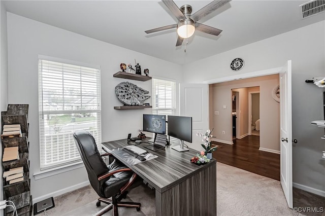 carpeted office space featuring visible vents, baseboards, and ceiling fan