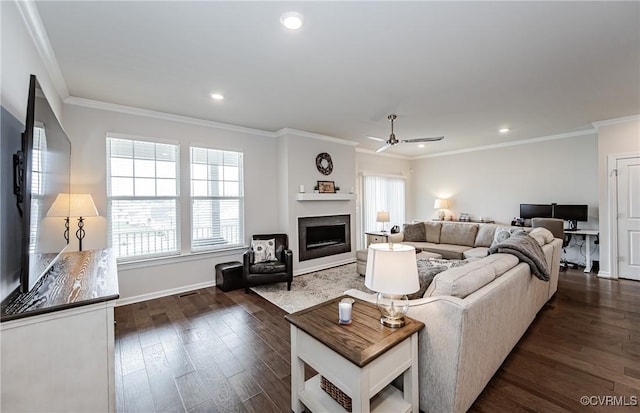 living area featuring dark wood-type flooring, a ceiling fan, recessed lighting, a fireplace, and crown molding