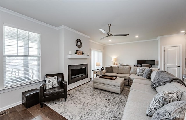 living area featuring visible vents, a fireplace, wood finished floors, and crown molding