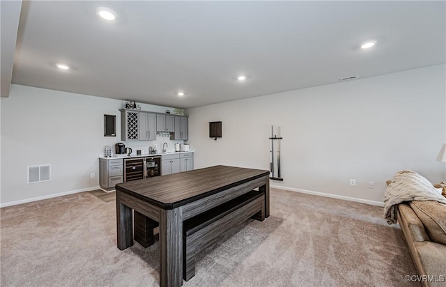 interior space with wet bar, wine cooler, light colored carpet, and visible vents