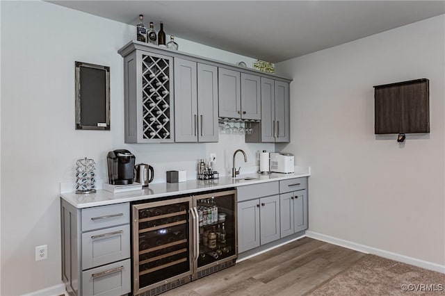 bar with indoor wet bar, beverage cooler, baseboards, and a sink