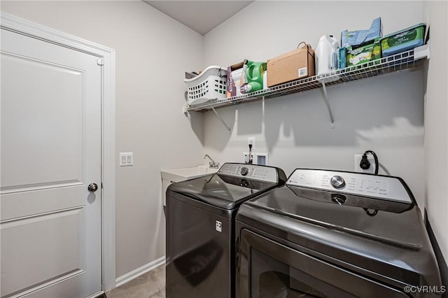 laundry area with a sink, washing machine and dryer, light tile patterned floors, baseboards, and laundry area