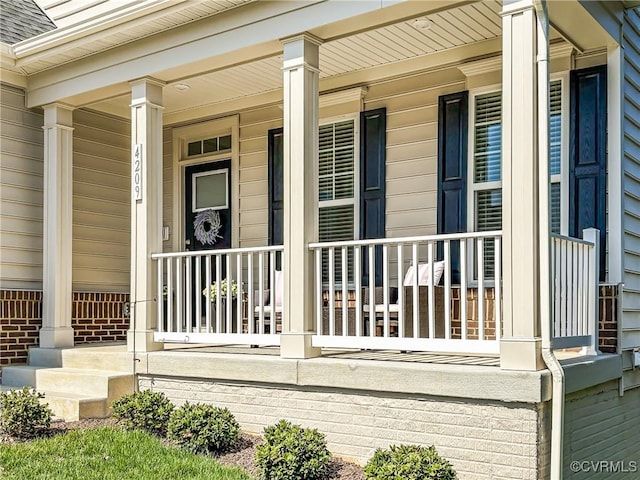 view of exterior entry featuring a porch and a shingled roof