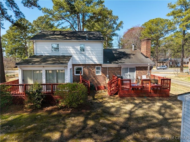 back of house featuring a wooden deck, brick siding, a yard, and a chimney