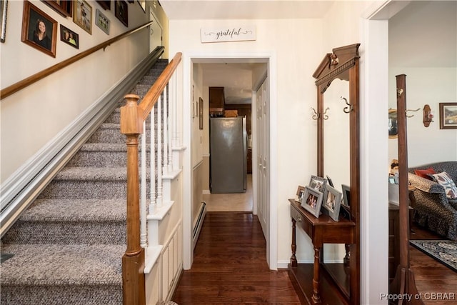 stairway featuring a baseboard heating unit and wood finished floors