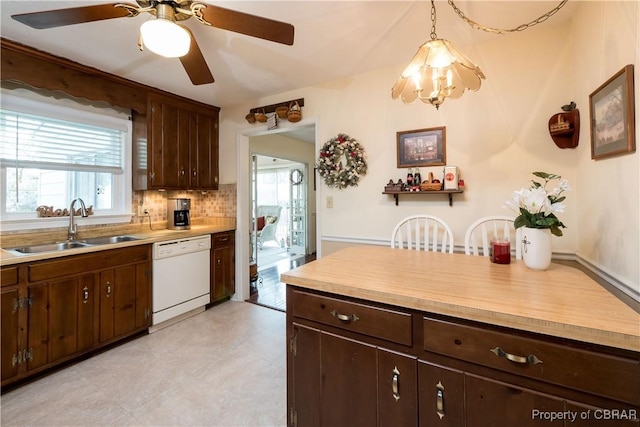 kitchen featuring a sink, backsplash, dark brown cabinets, dishwasher, and ceiling fan