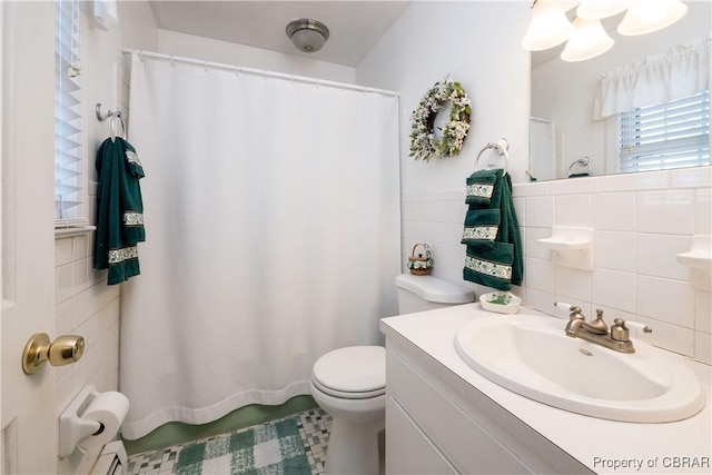 bathroom featuring vanity, tile walls, and toilet