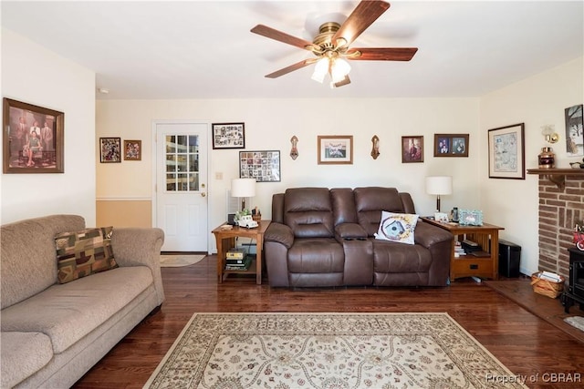 living room featuring dark wood-style floors, a wood stove, and a ceiling fan