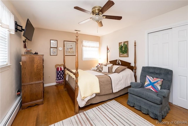 bedroom featuring baseboards, ceiling fan, wood finished floors, a closet, and a baseboard radiator