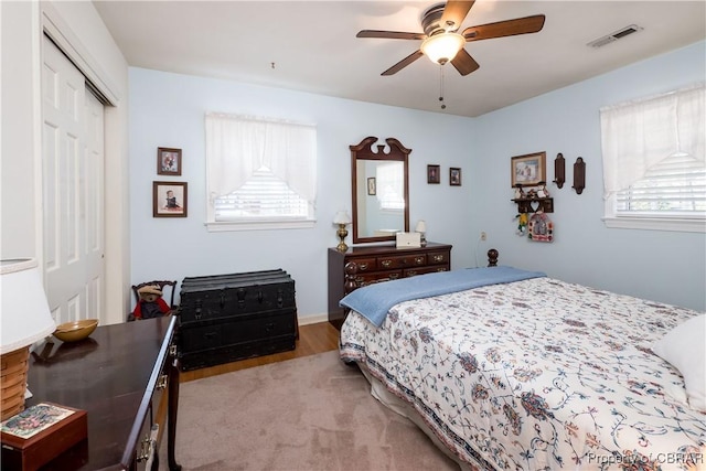 bedroom with light wood finished floors, a ceiling fan, visible vents, and a closet