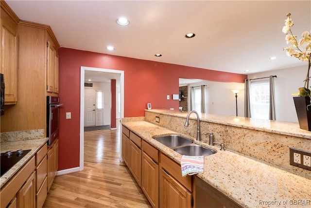 kitchen with light wood-style flooring, a sink, recessed lighting, stainless steel oven, and light stone countertops