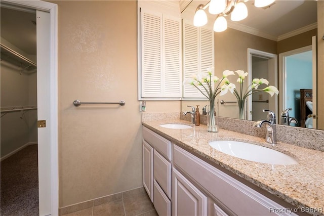 bathroom with tile patterned flooring, crown molding, double vanity, and a sink